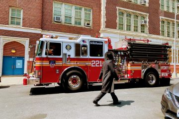 A firetruck in front of a building and a man walking in front of it